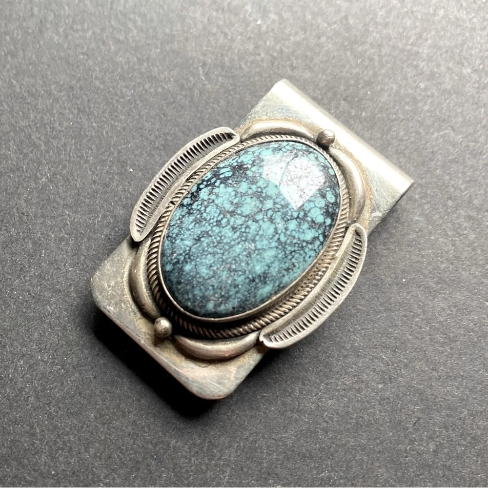 Silver toned money clip with polished blue stone. No stamps.
